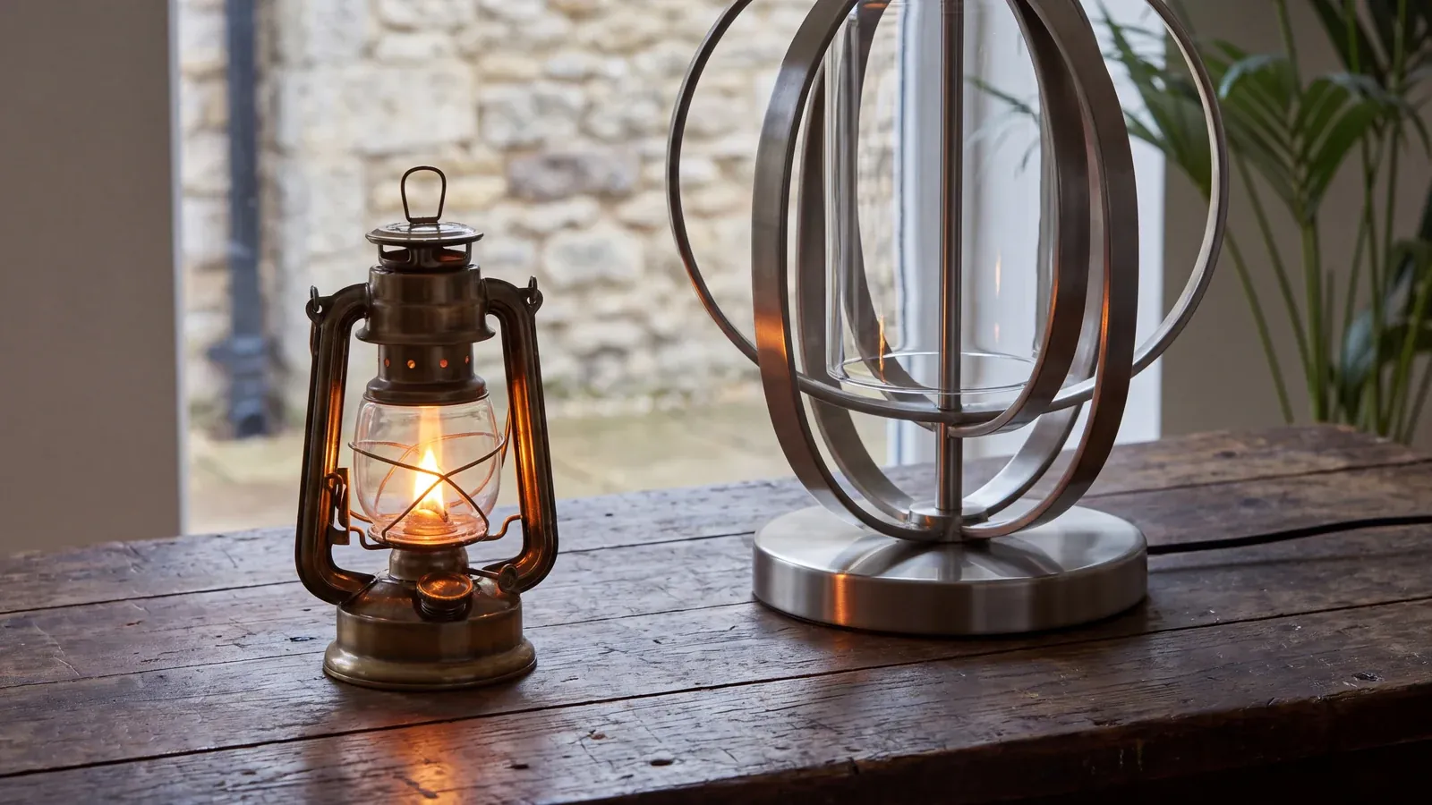 A lit antique oil lantern beside a modern lamp on a wooden table: a 1960s medicine that is still in use
